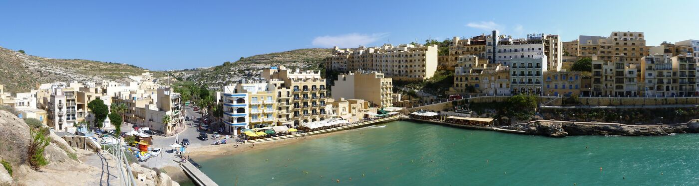 Xlendi bay, with the beach and the restaurants along the water at the head of it.